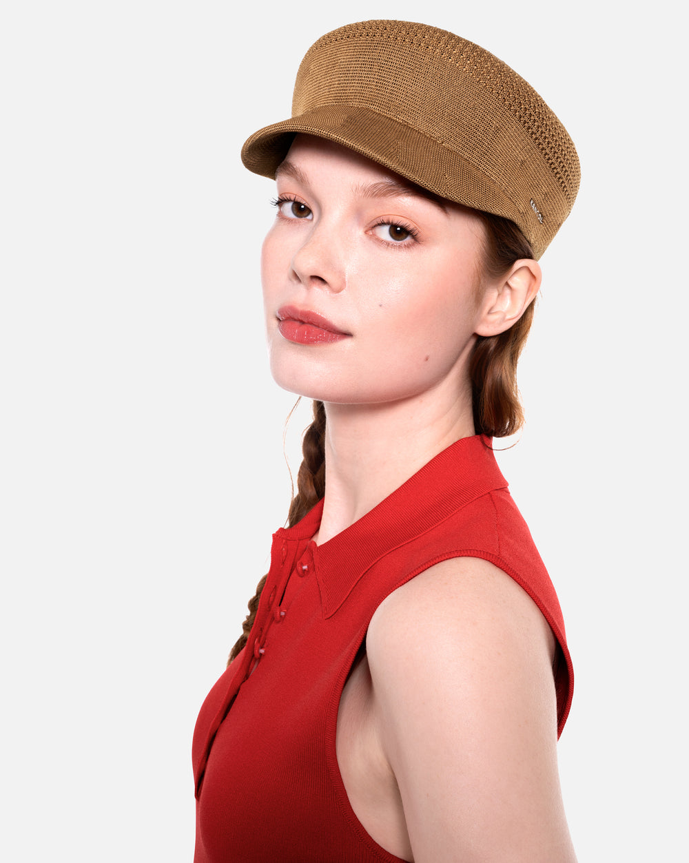 Woman wearing a brown cap and red sleeveless top on a white background