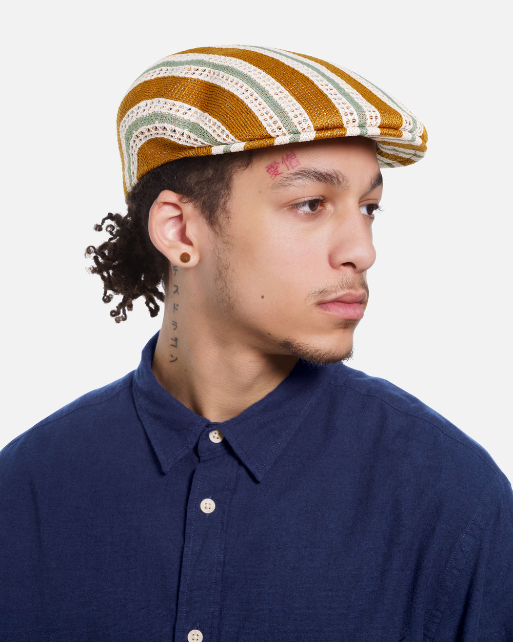 Man wearing a striped flat cap and navy shirt on a white background