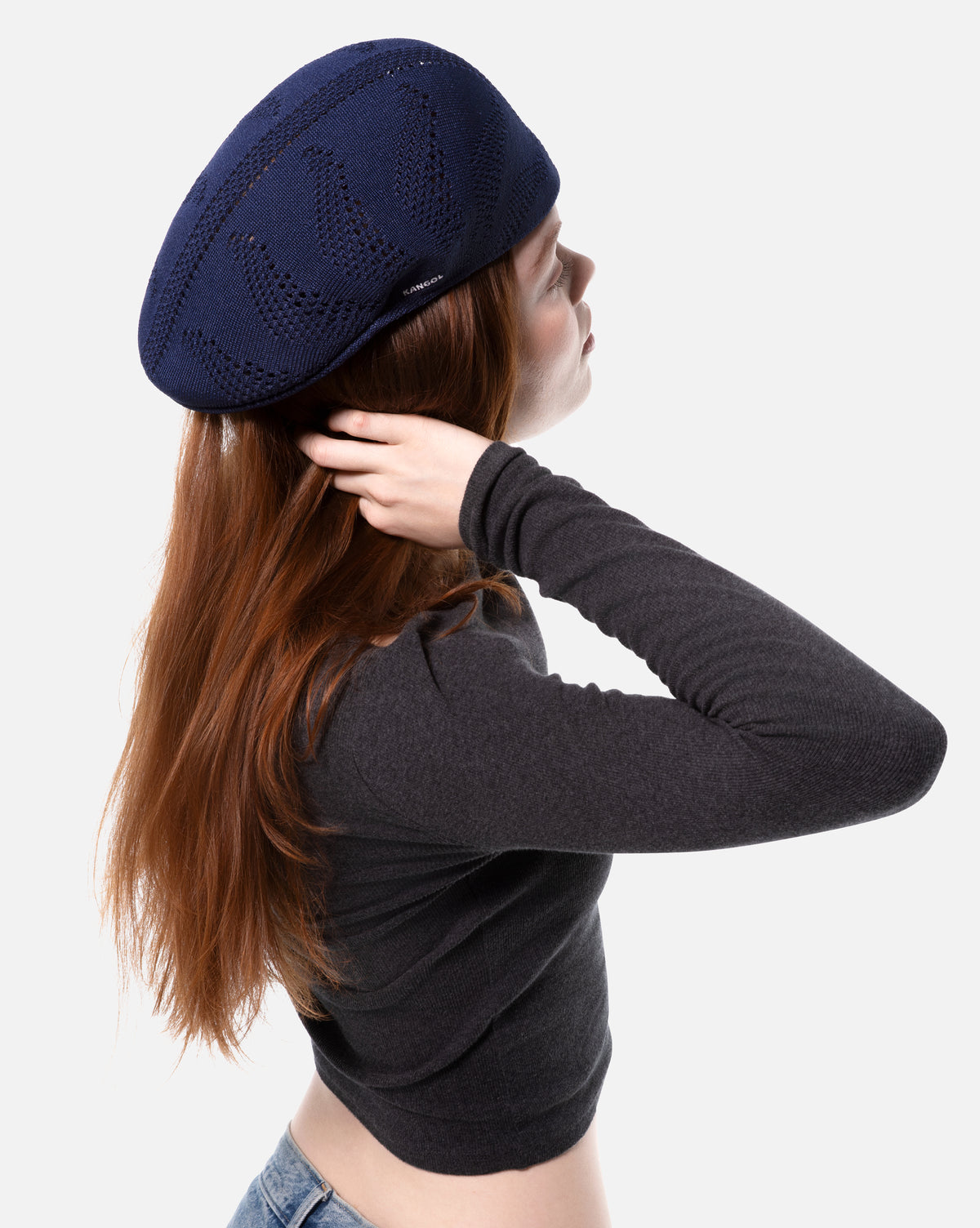 Person wearing a navy blue knitted flat cap on a white background