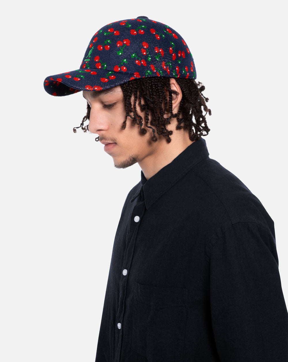 Person wearing a cap with cherry pattern on a plain background
