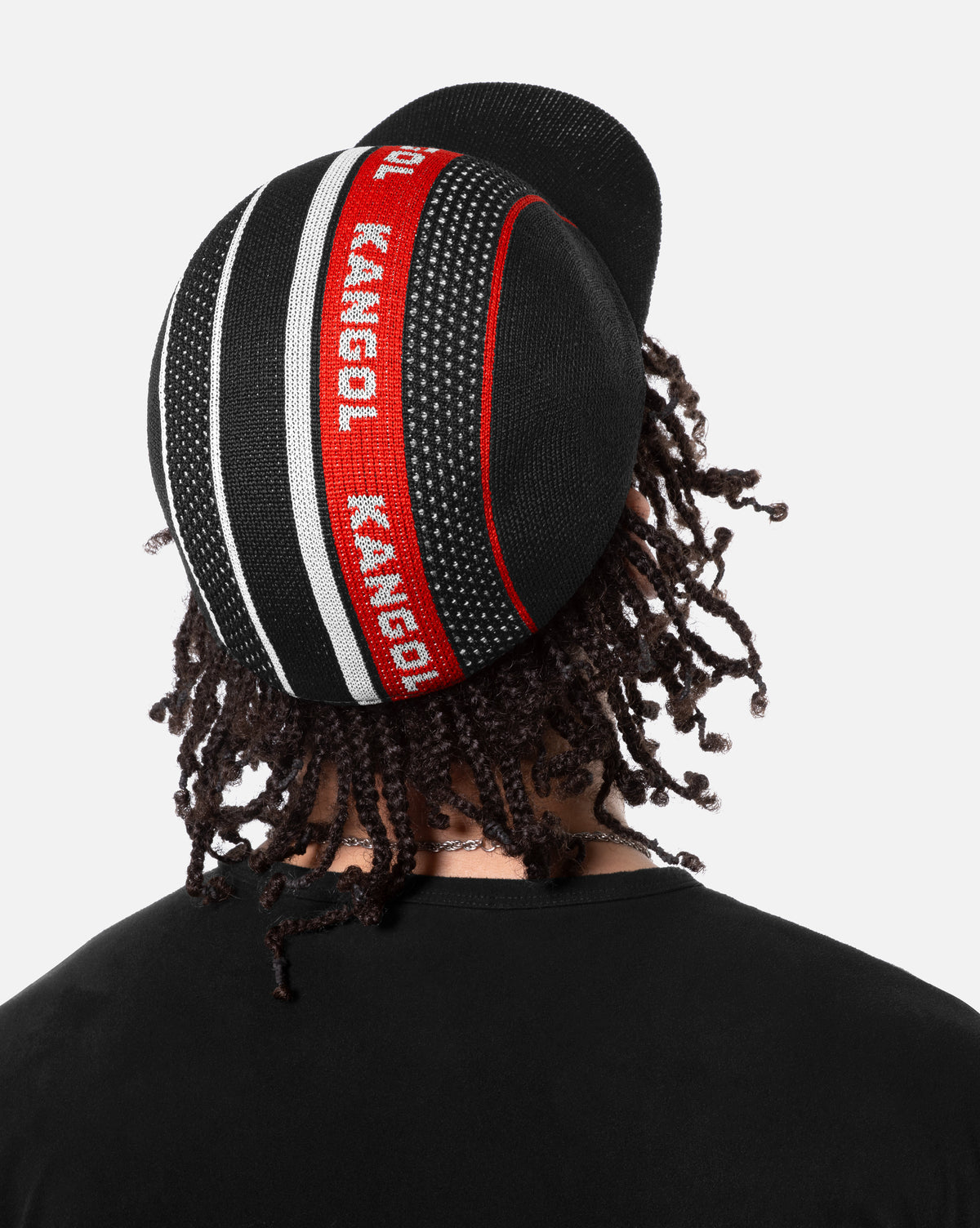 Person wearing a black baseball hat with red and white Kangol branding on back of the hat on a white background