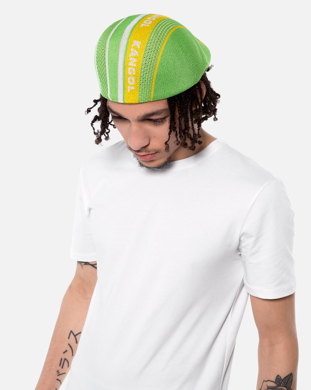Person wearing a green and yellow beanie with 'Kangol' branding on a white background