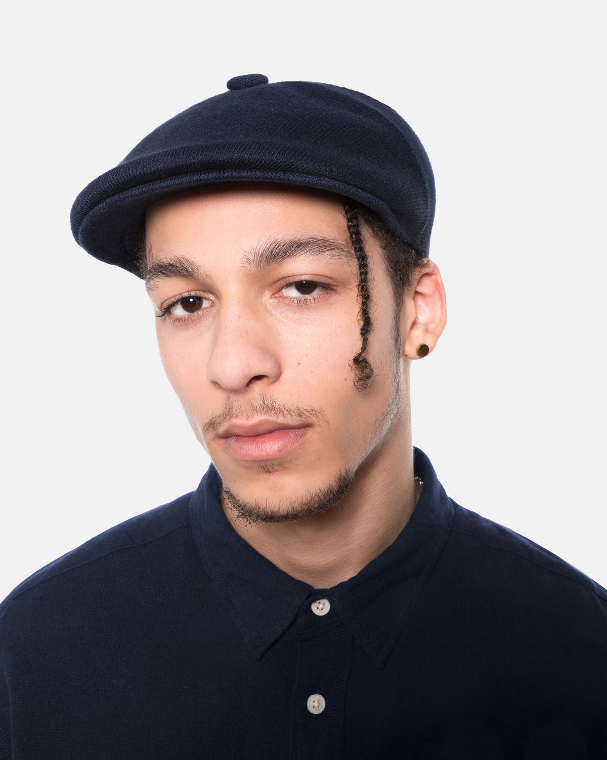 Man wearing a navy flat cap against a white background