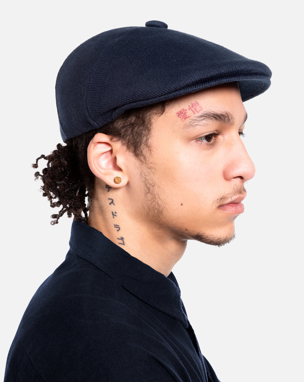 Person wearing a navy flat cap against a white background
