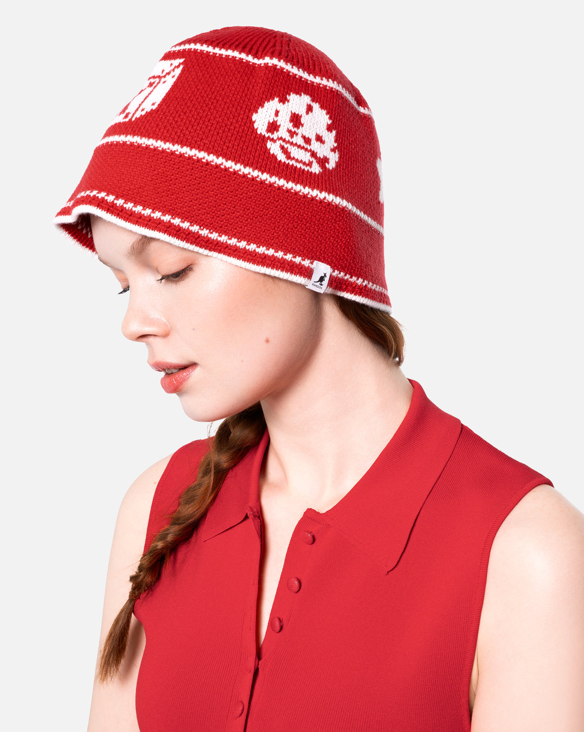 Person wearing a red knit hat with white patterns on a white background