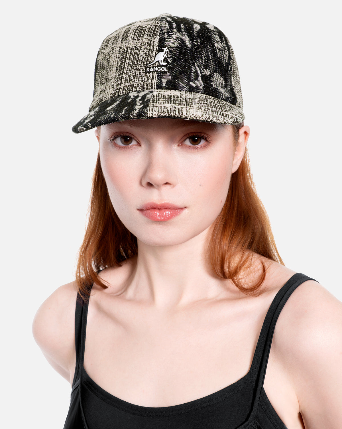Woman wearing a black denim patchwork cap with a logo on a white background