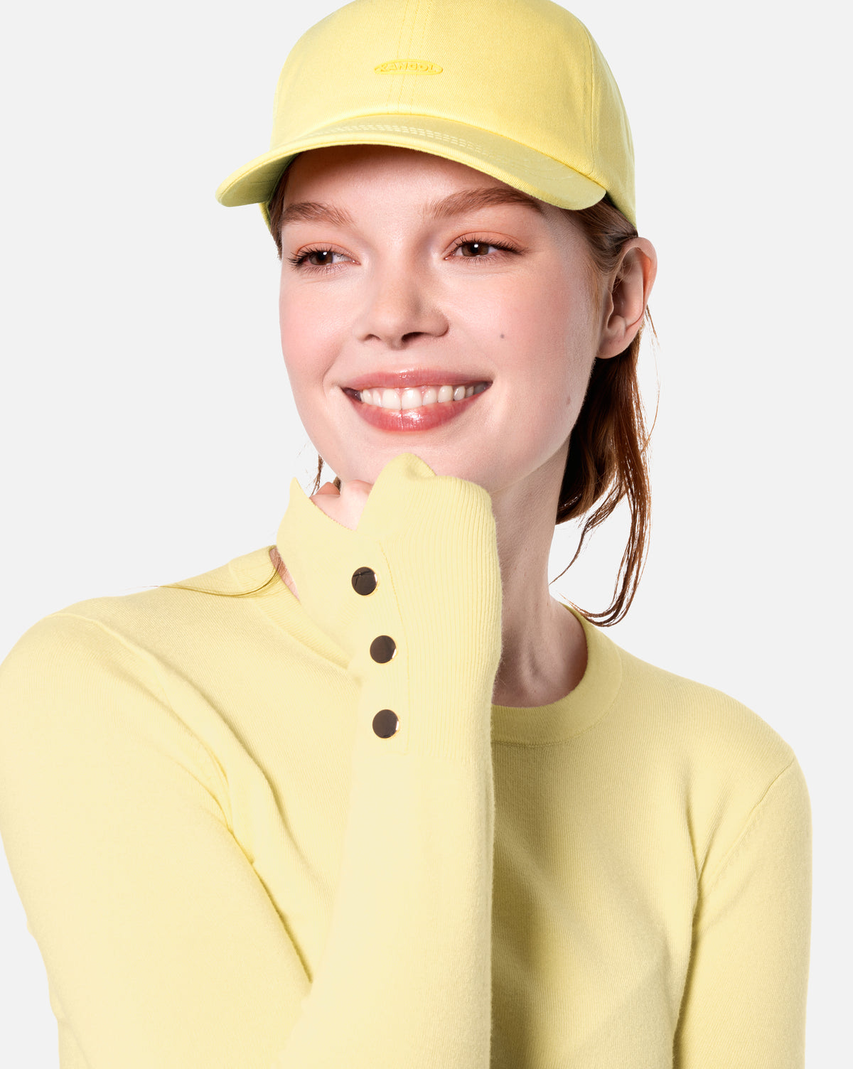Person wearing a yellow cap and matching outfit on a light gray background