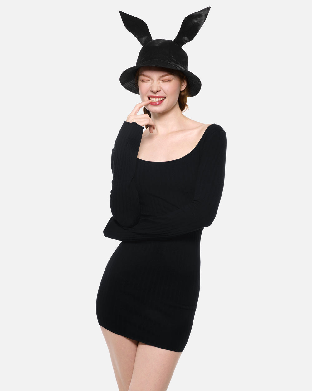Person wearing a black dress and black bucket hat with bunny ears on a white background