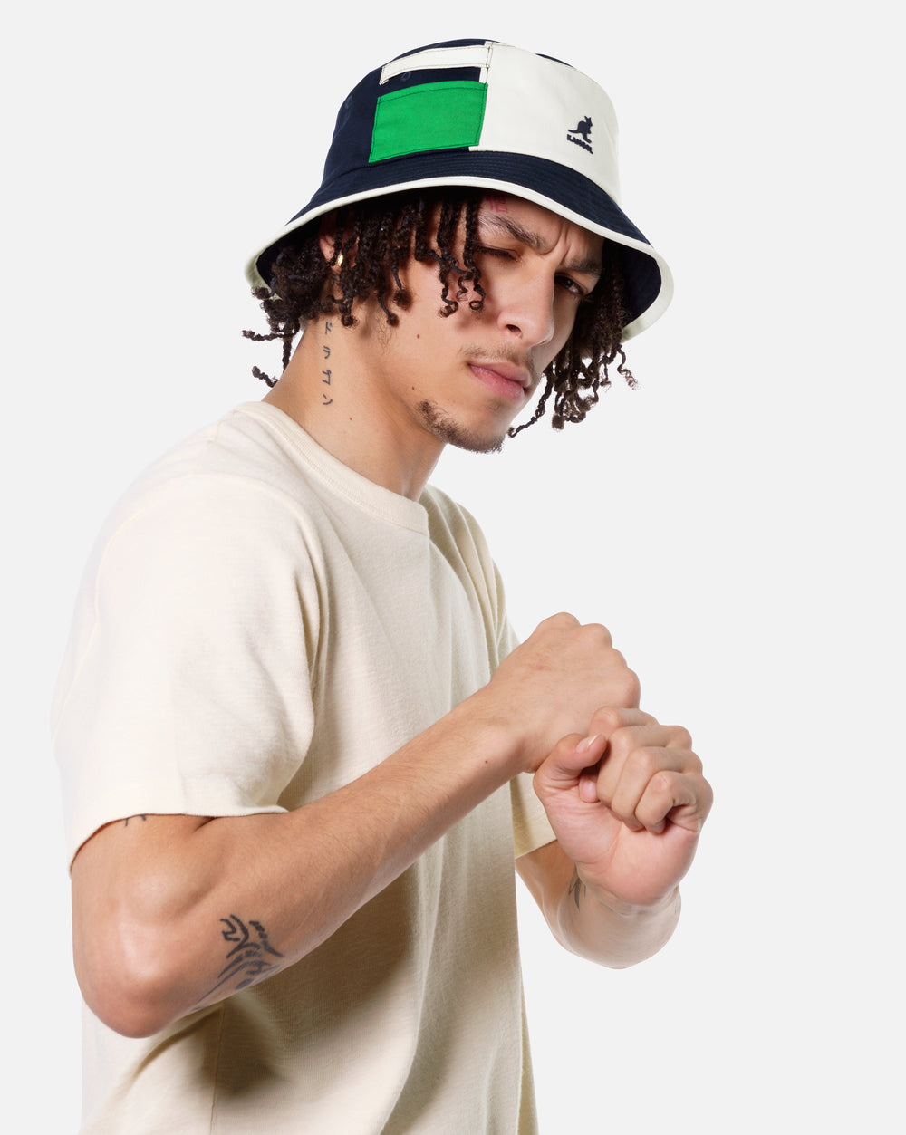 Person wearing a navy colorblock bucket hat with green accents on a white background