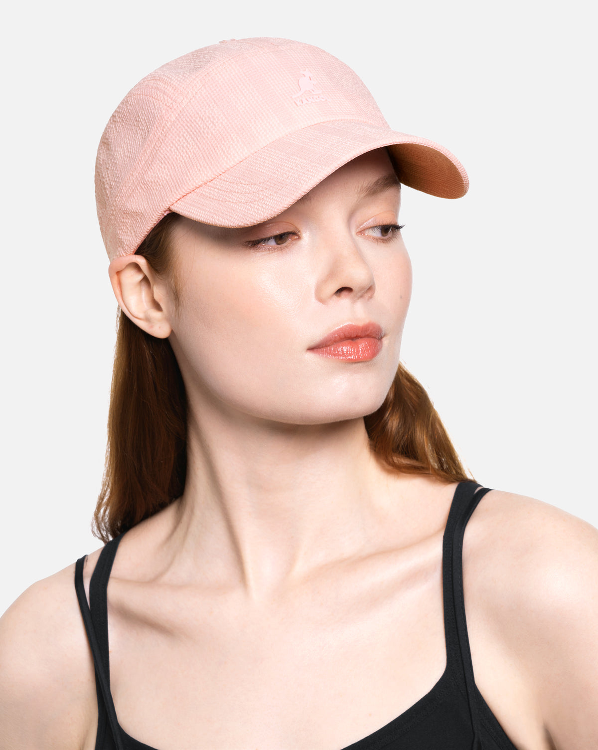 Woman wearing a pink cap against a plain background