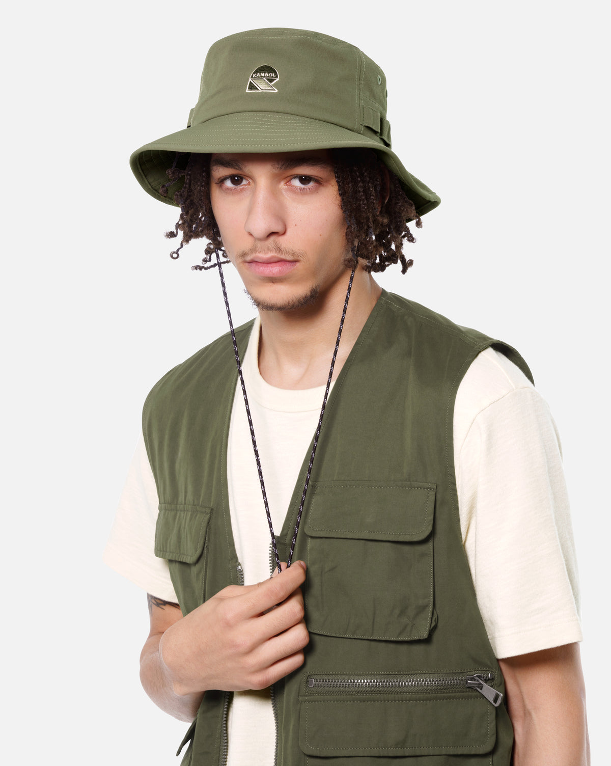 Person wearing a green bucket hat and vest on a white background