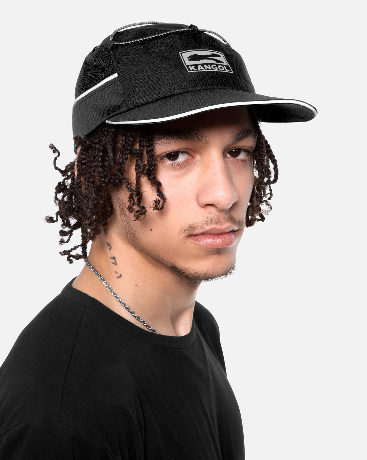 Person wearing a black Kangol cap on a white background