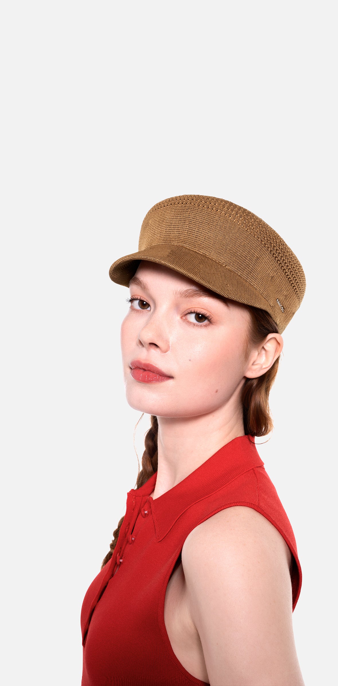 Woman wearing a brown cap and red sleeveless top on a white background