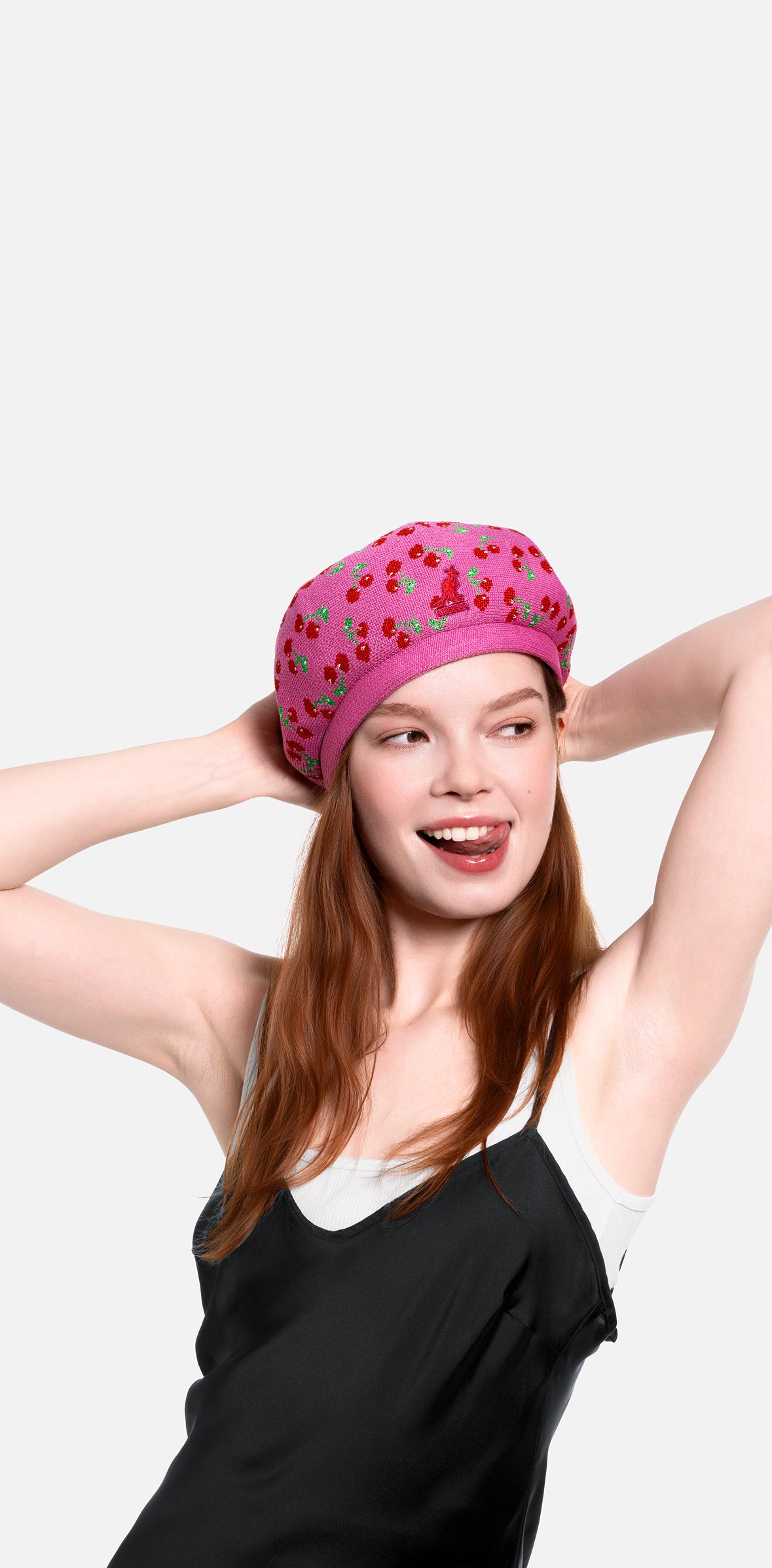 Woman wearing a pink cherry print beret on a white background