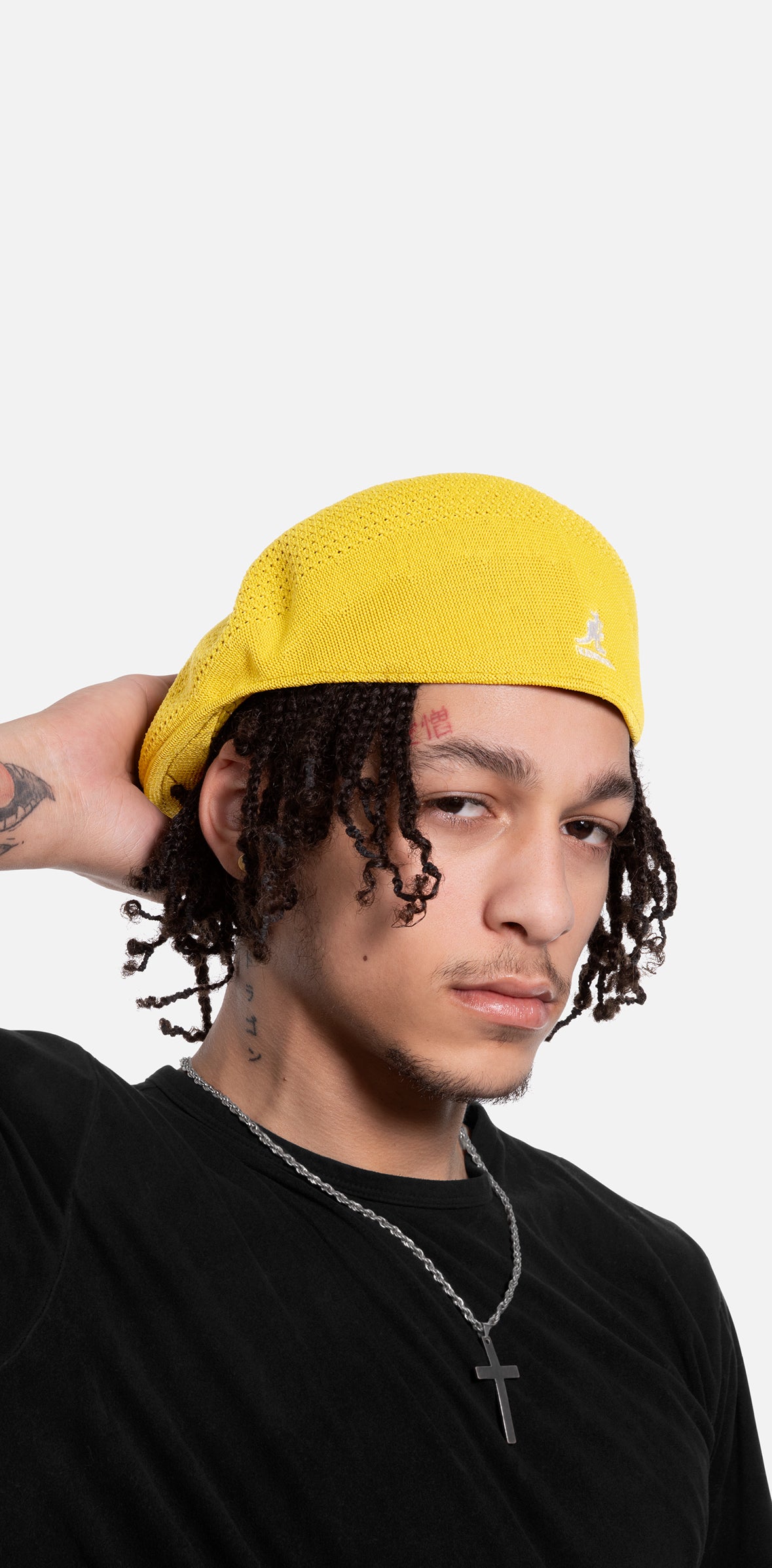 Person wearing a yellow cap with a Kangol logo on a white background