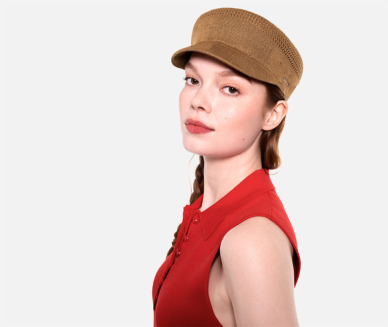 Woman wearing a brown cap and red sleeveless top on a white background
