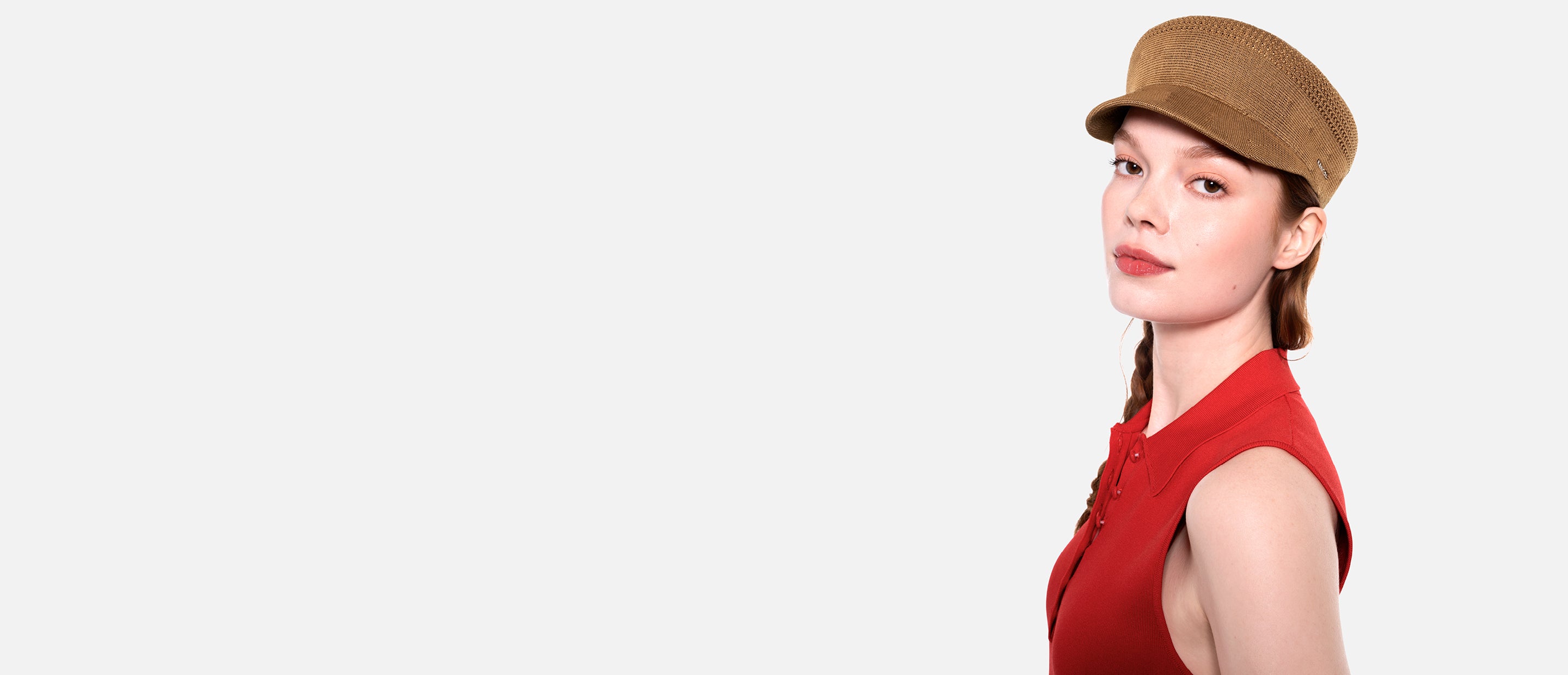 Woman wearing a red sleeveless top and brown cap on a white background